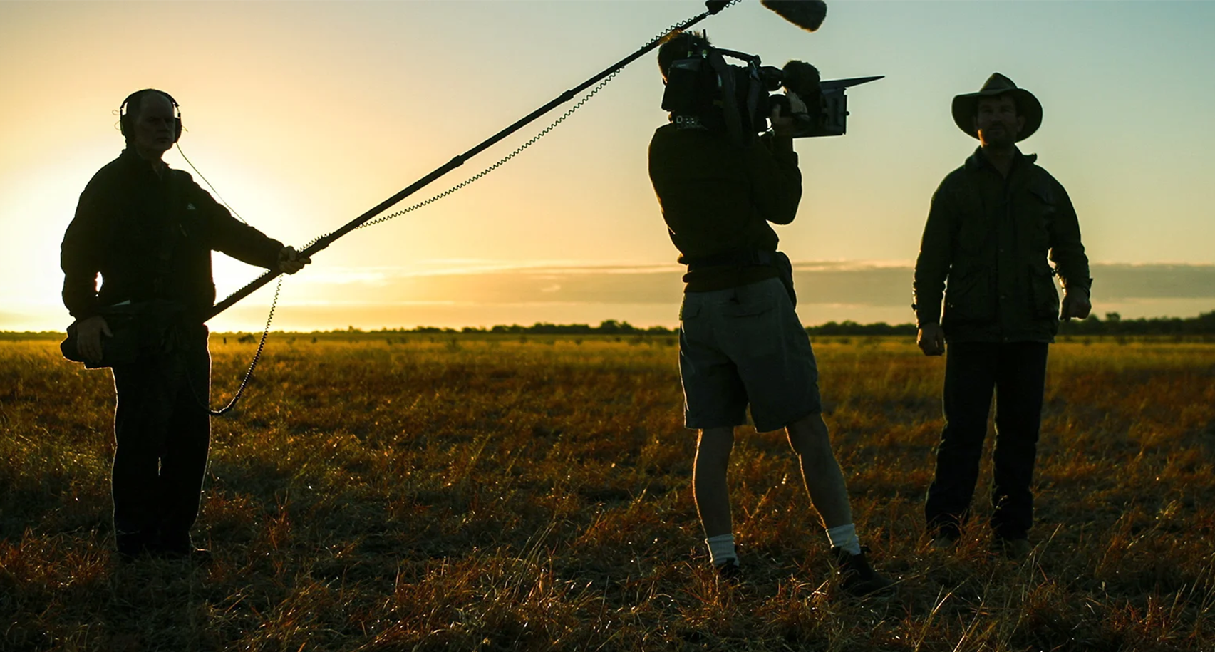 A film shoot on location with the outlines of a boom mic operator